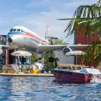 Ein großes Flugzeug hängt an einem Gebäude über einem Pool