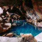 Eine Höhle mit einem blauen Wasserbecken in der Mitte