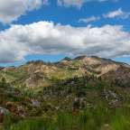 Ein Berg mit einem blauen Himmel und weißen Wolken dahinter