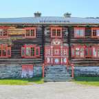 Ein altes Holzhaus mit roten Fenstern und einer roten Tür