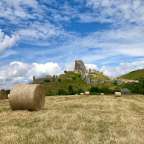Ein Feld mit Heuballen und ruinen im Hintergrund