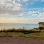 Ein kleines gelbes Haus steht auf einem Hügel mit Blick auf das Meer