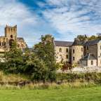 Ein großes Gebäude mit einer Kirche dahinter steht neben einem Fluss