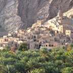 Ein kleines Dorf auf einem Hügel mit Palmen umgeben