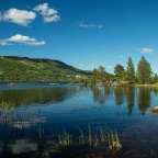 Ein See mit Bäumen und Bergen im Hintergrund