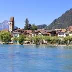 Eine Reihe von Häusern neben einem Fluss mit einem Uhrturm im Hintergrund