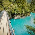 Eine Hängebrücke über einen Fluss mit blauem Wasser
