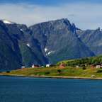 Ein kleines Dorf an der Küste mit Bergen im Hintergrund