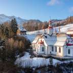 Eine weiße Kirche mit einem roten Dach steht auf einem schneebedeckten Hügel