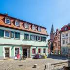 Ein grünes Gebäude mit grünen Fensterläden und einem roten Schild davor