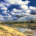 Ein Fluss mit einem blauen Himmel und weißen Wolken darüber