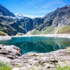 Ein See inmitten einer Bergkette mit einem Wasserfall im Hintergrund