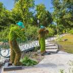 Eine Statue eines Mannes mit blauem Hut steht neben einer Brücke