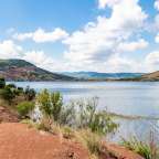 Ein See mit Bergen im Hintergrund und einem blauen Himmel mit Wolken