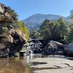 Ein Wasserfall inmitten eines Waldes mit einem Berg im Hintergrund