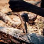 Ein Mann formt mit einem Hammer und einem Stechbeitel ein Stück Holz.