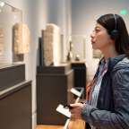 Eine Frau schaut in einem Museum auf ein Gemälde