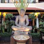 Eine Statue eines Buddhas sitzt in einer Lotusposition vor einem Restaurant