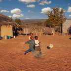 Drei Kinder spielen mit einem Fußball auf einem Feld