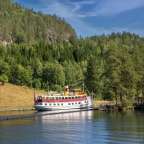 Ein rot-weißes Boot fährt auf einem Fluss