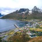 Ein kleines Dorf an der Küste mit Bergen im Hintergrund