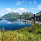 Eine Holzbrücke über einen See mit Bergen im Hintergrund