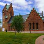 Eine rote Backsteinkirche mit einem grünen Dach