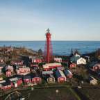 Ein kleines Dorf mit roten Häusern und einem Leuchtturm