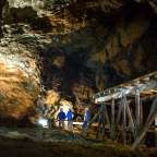 Zwei Männer stehen in einer Höhle neben einer Holzbrücke