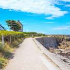 Ein Pfad führt zu einem weißen Haus an der Küste