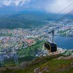 Eine Seilbahn fährt über eine Stadt mit einem See im Hintergrund