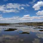 Ein Fluss mit einem blauen Himmel und weißen Wolken darüber
