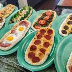 Verschiedene Pizzen stehen auf grünen Tellern auf einem Tisch