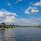Ein Fluss mit einem blauen Himmel und weißen Wolken