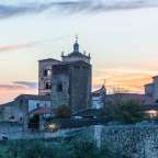 Ein kleines Dorf mit einer Kirche und einem Turm bei Sonnenuntergang