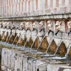 Eine Reihe von Brunnen mit Löwenköpfen darauf