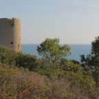 Ein Turm steht auf einem Hügel mit Blick auf das Meer