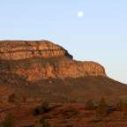 Ein voller Mond steigt über einen felsigen Berg