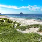 Ein weißer sandiger Strand mit einem Berg im Hintergrund