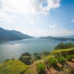 Ein großer See umgeben von Bergen und Bäumen an einem sonnigen Tag