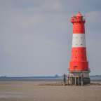 Ein rot-weißer Leuchtturm steht in der Mitte eines Sees