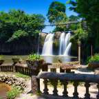 Ein Wasserfall mit einer Hängebrücke im Hintergrund