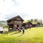 Eine Gruppe von Menschen steht vor einem Holzhaus mit grünem Dach
