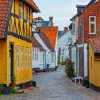 Eine Straße mit gelben Gebäuden und roten Backsteinhäusern