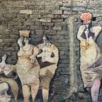 Ein Gemälde an einer Backsteinmauer zeigt eine Gruppe von Frauen
