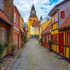 Eine schmale Straße mit bunten Häusern und einer Kirche im Hintergrund