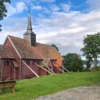 Eine kleine rote Kirche auf einem Hügel mit Blick auf einen See