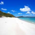 Ein Strand mit weißem Sand und blauem Wasser