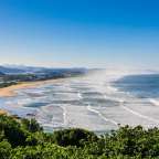 Ein Strand mit vielen Wellen und Bergen im Hintergrund
