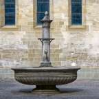 Ein Brunnen steht vor einer Backsteinmauer